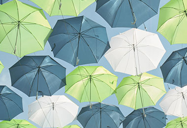 green, blue, and white umbrellas floating in a clear blue sky