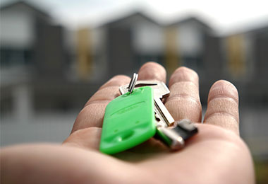 closeup of an outstretched hand holding keys on a green keychain