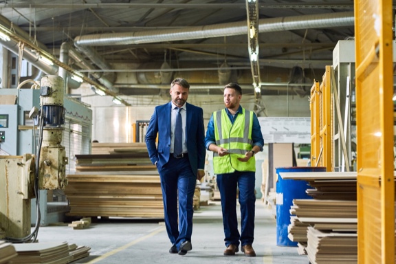 a man in a suit walks with a man in a construction vest